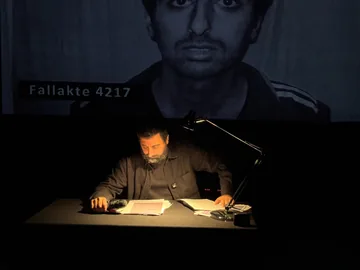 عامر مطر يقرأ من إضبارة 4217 على المسرح في هانوفر